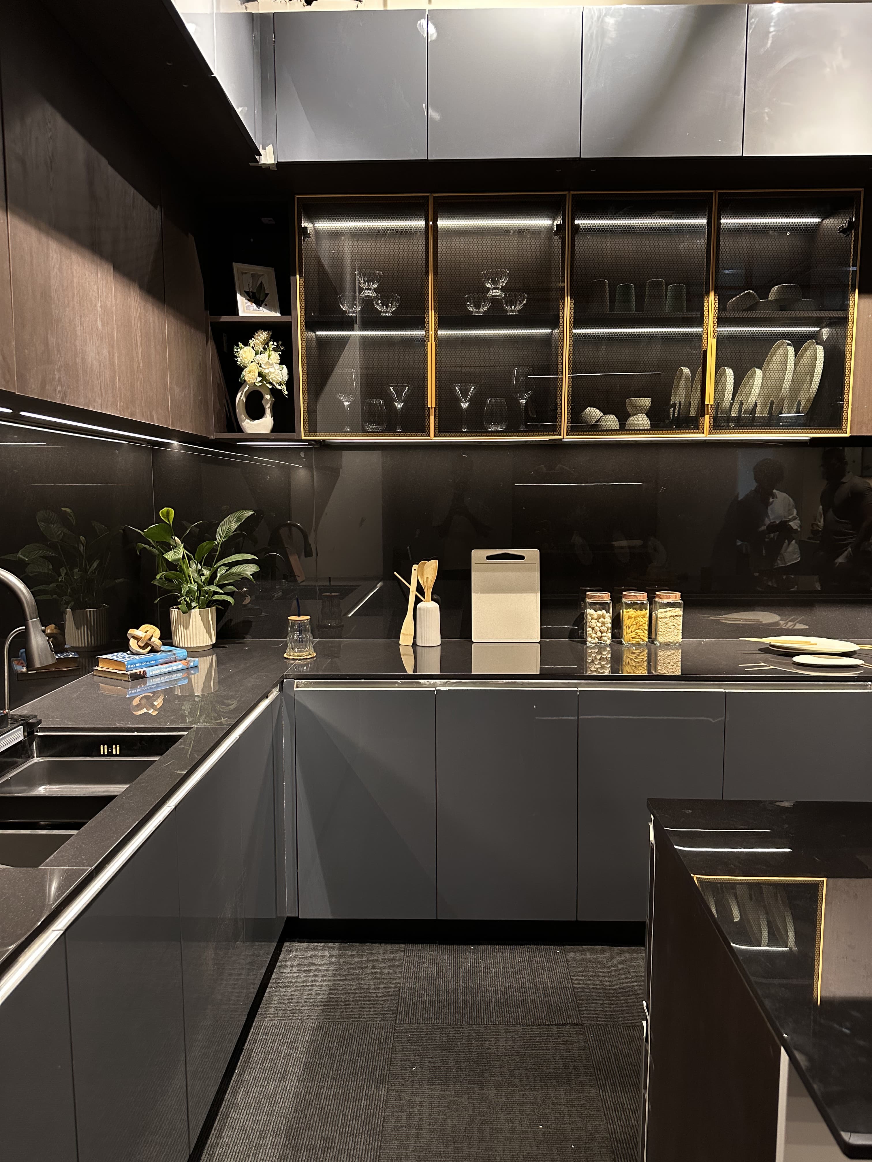 Glass-fronted kitchen storage with warm metal framing